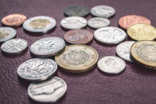 Small pile of various unique coins on a dark table.