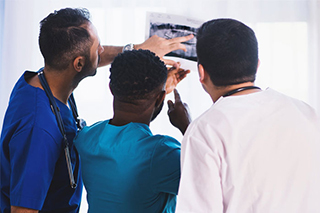 Three doctors analyzing a printed x-ray.