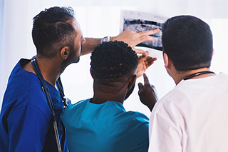 Three doctors analyzing a printed x-ray.