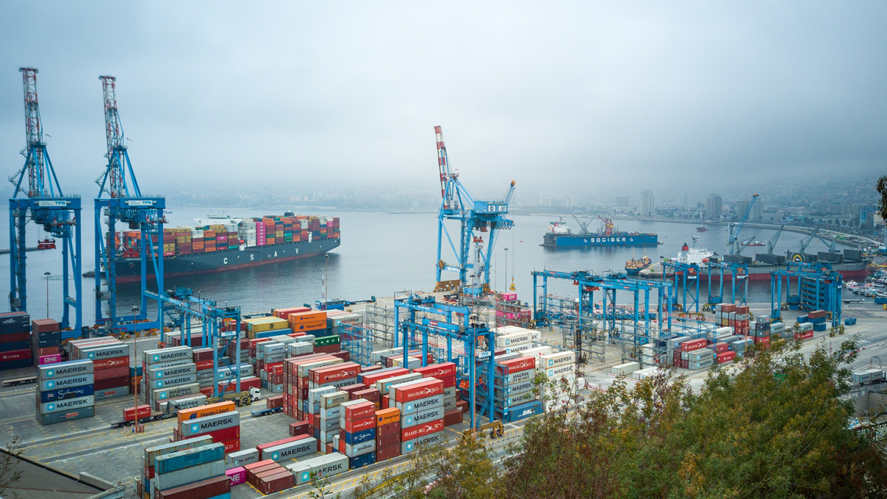 Loading dock with storage containers and large cargo ships in the water.